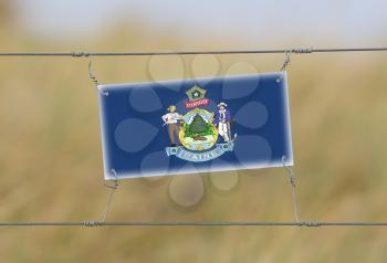 Border fence - Old plastic sign with a flag - Maine