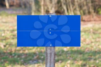 Blank blue road sign standing in a field