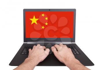 Hands working on laptop showing on the screen the flag of China