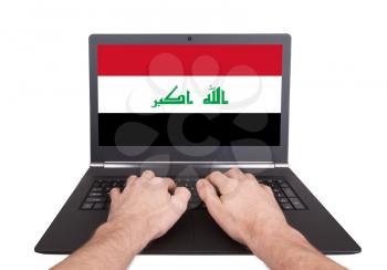 Hands working on laptop showing on the screen the flag of Iraq