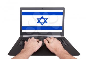 Hands working on laptop showing on the screen the flag of Israel