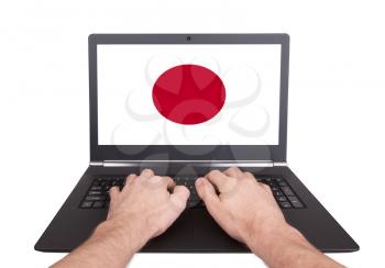 Hands working on laptop showing on the screen the flag of Japan