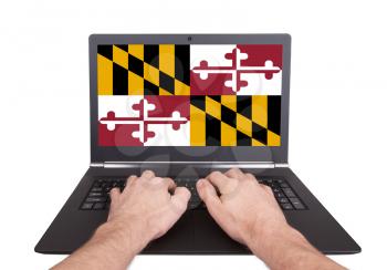 Hands working on laptop showing on the screen the flag of Maryland