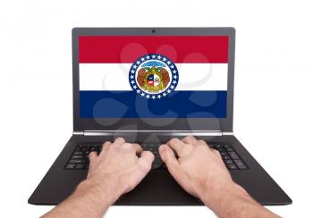 Hands working on laptop showing on the screen the flag of Missouri
