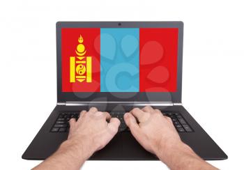 Hands working on laptop showing on the screen the flag of Mongolia