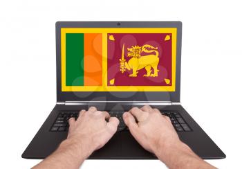 Hands working on laptop showing on the screen the flag of Sri Lanka