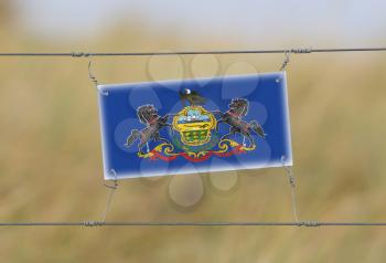 Border fence - Old plastic sign with a flag - Pennsylvania