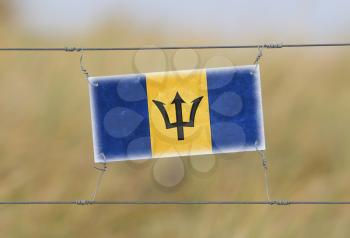 Border fence - Old plastic sign with a flag - Barbados