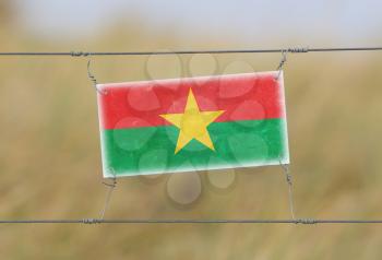Border fence - Old plastic sign with a flag - Burkina Faso