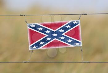 Border fence - Old plastic sign with a flag - Confederate flag