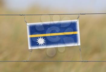 Border fence - Old plastic sign with a flag - Nauru