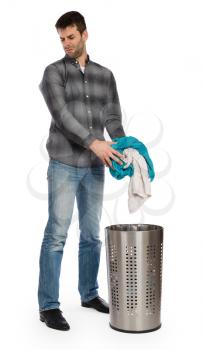 Young man putting a dirty towel in a laundry basket, isolated