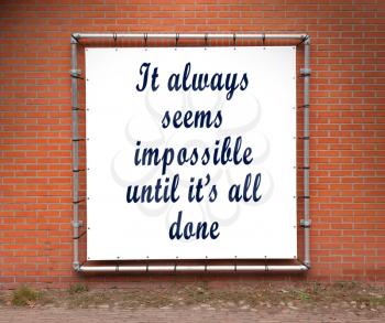 Large banner with inspirational quote on a brick wall - It always seems impossible until it's all done