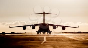 Large military cargo plane silhouette on an empty airstrip