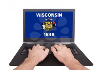 Hands working on laptop showing on the screen the flag of Wisconsin