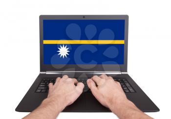 Hands working on laptop showing on the screen the flag of Nauru