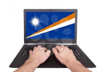 Hands working on laptop showing on the screen the flag of Marshall Islands