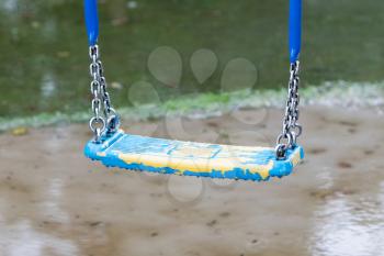 Old plastic swing hanging over a puddle