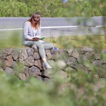 Women sitting near riverside, reading a book