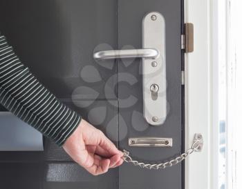 Door chain on a grey door, security measures