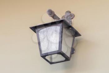 Vintage looking metal lantern with modern lamp inside hanging on an old wall