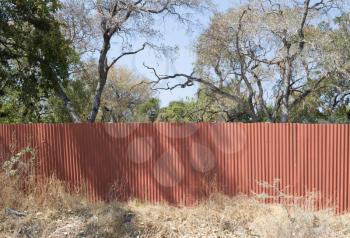 Red metal fence, protecting the property in Botswana