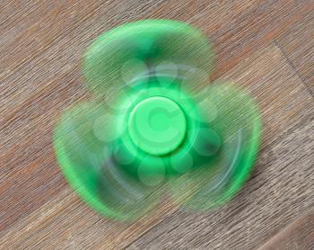 Image of Fidget finger spinner stress toy - Green spinner on a wooden desk