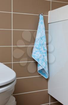 Small blue towel in a bathroom, next to the toilet