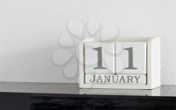 White block calendar present date 11 and month January on white wall background