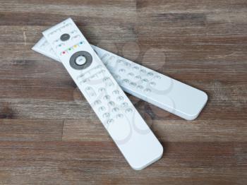 Two white remotes on a wooden table