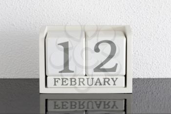 White block calendar present date 12 and month February on white wall background