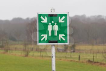 Green plastic 'assembly point' sign, dutch landscape in the background