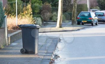 Rolling trash can standing at the side of the road