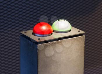 Red and green button on a concrete pillar