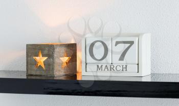 White block calendar present date 7 and month March on white wall background
