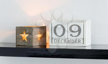 White block calendar present date 9 and month December on white wall background