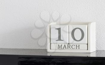 White block calendar present date 10 and month March on white wall background