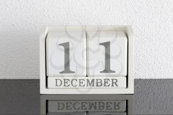 White block calendar present date 11 and month December on white wall background
