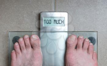 Closeup of man's feet on weight scale - Too much