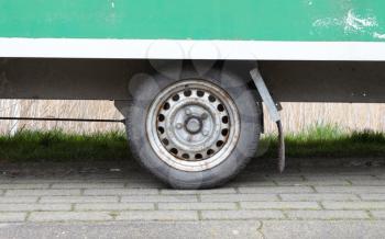 Wheel of an old green wooden trailer on wheels stands at the side of the road, the Netherlands