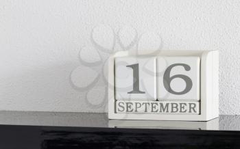 White block calendar present date 16 and month September on white wall background