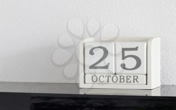 White block calendar present date 25 and month October on white wall background