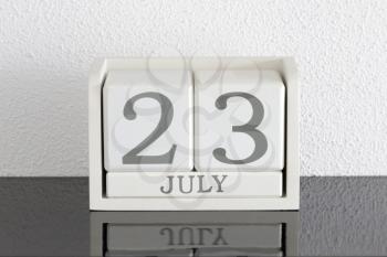 White block calendar present date 23 and month July on white wall background
