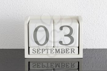 White block calendar present date 3 and month September on white wall background