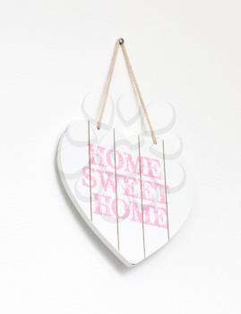 Text home sweet home in a heart-shaped signboard - Hanging on a white wall