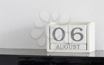 White block calendar present date 6 and month August on white wall background