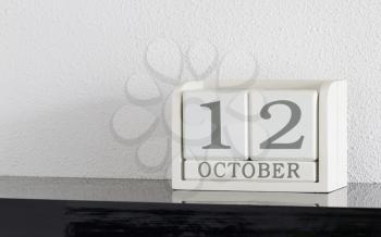 White block calendar present date 12 and month October on white wall background