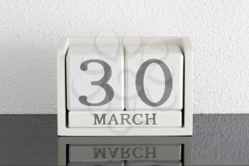 White block calendar present date 30 and month March on white wall background
