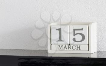 White block calendar present date 15 and month March on white wall background