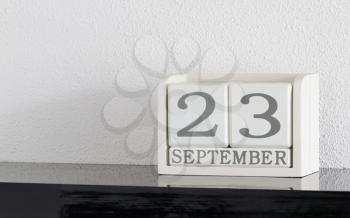 White block calendar present date 23 and month September on white wall background